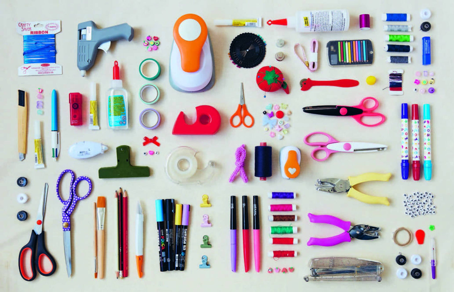 Assorted stationery items including scissors, markers, and glue sticks on a beige background