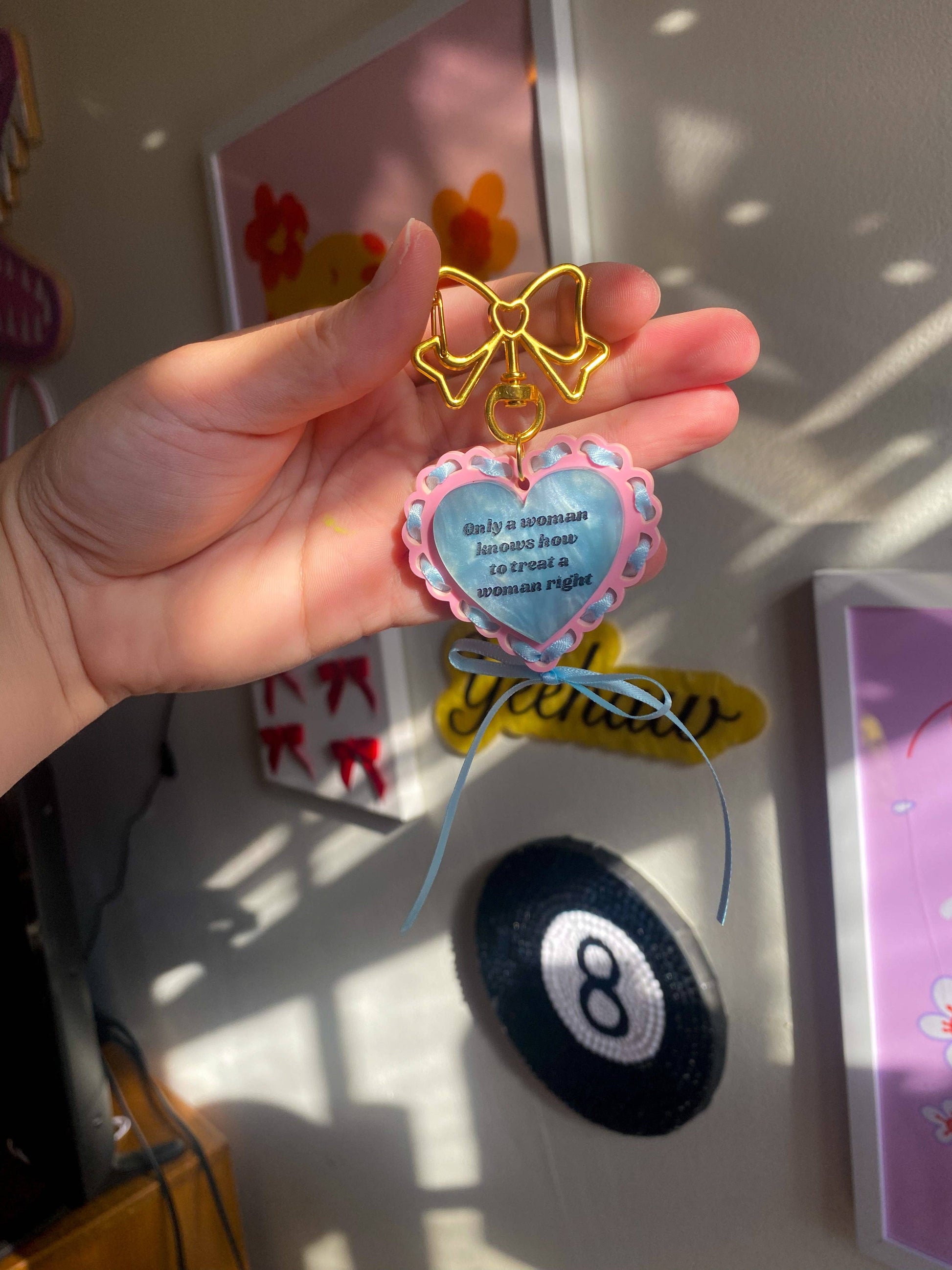 Baby blue acrylic keychain that says “She Gets the Job Done” with satin ribbon