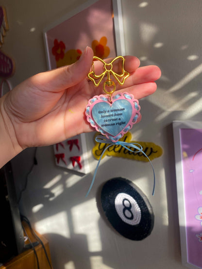 Baby blue acrylic keychain that says “She Gets the Job Done” with satin ribbon
